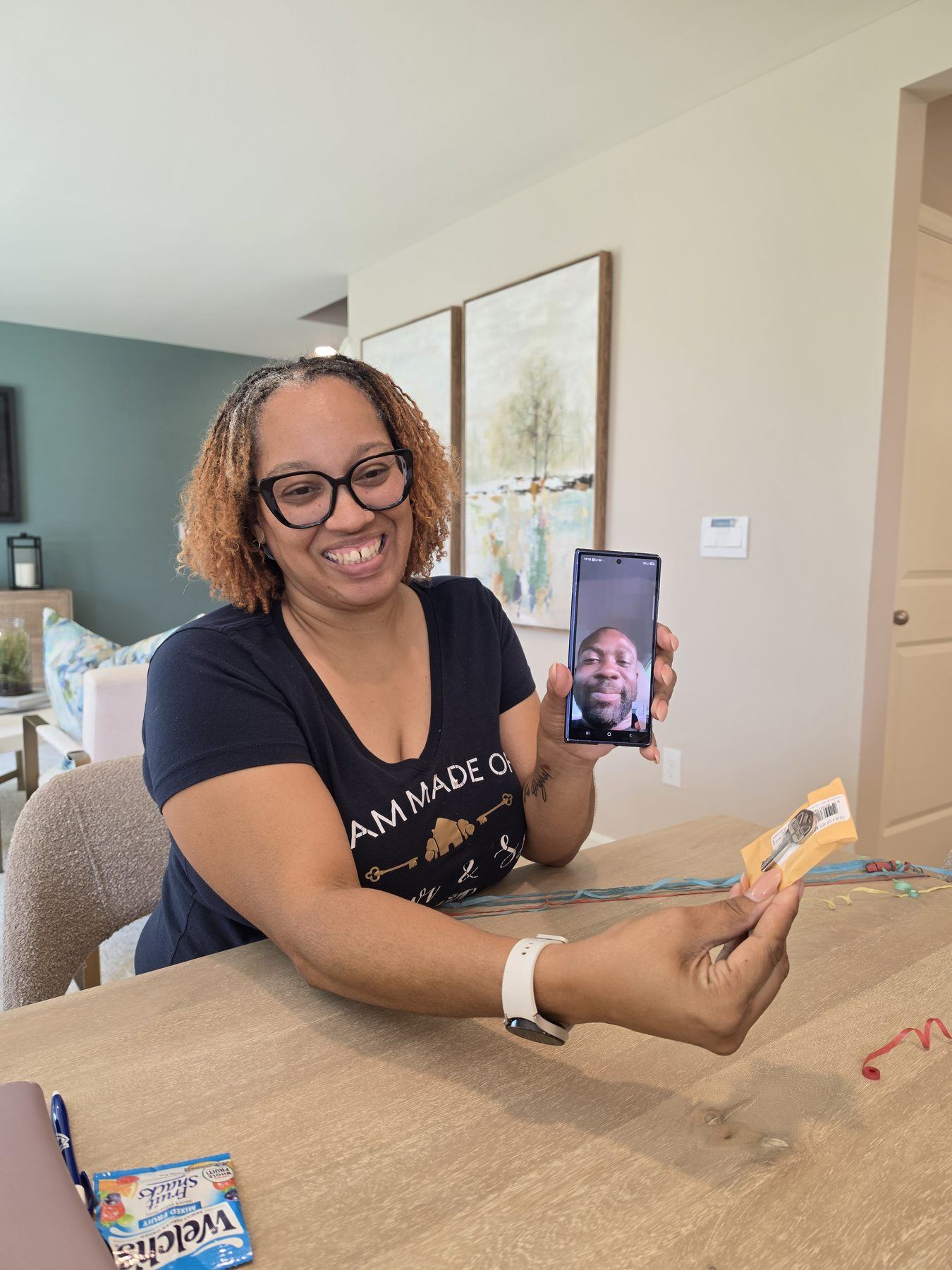 Homebuyer's mother holding up a house key while her son, serving overseas in the military, watches on a FaceTime call during the closing