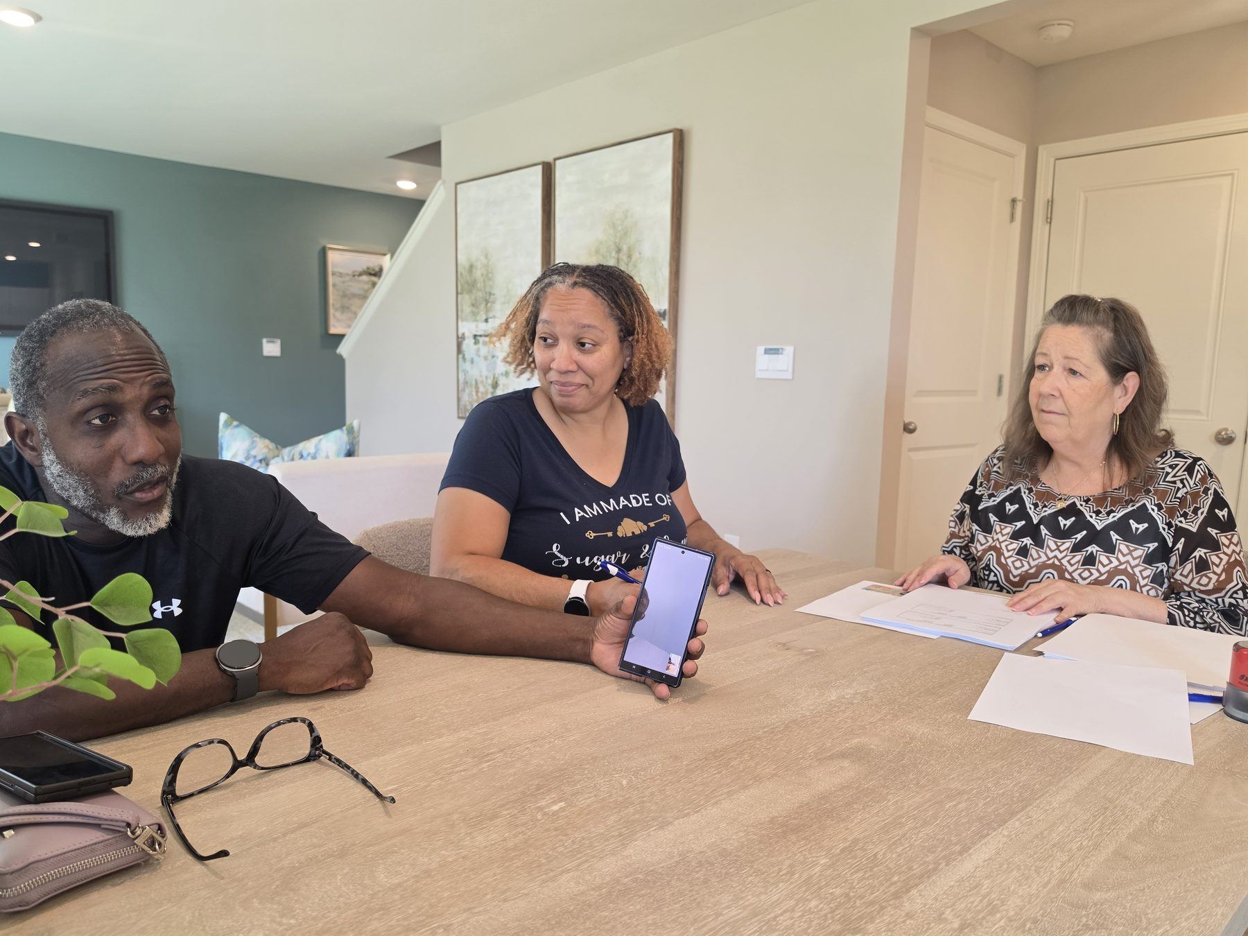 Parents and a closing team at the table holding a video call with their military son overseas during his home closing